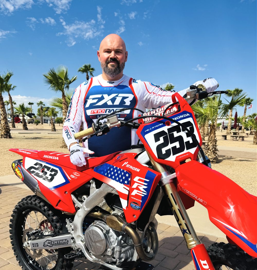 Darren Hillstead, founder of Throttle Relief Motorsports, standing with his red Honda CRF motocross bike, number 253